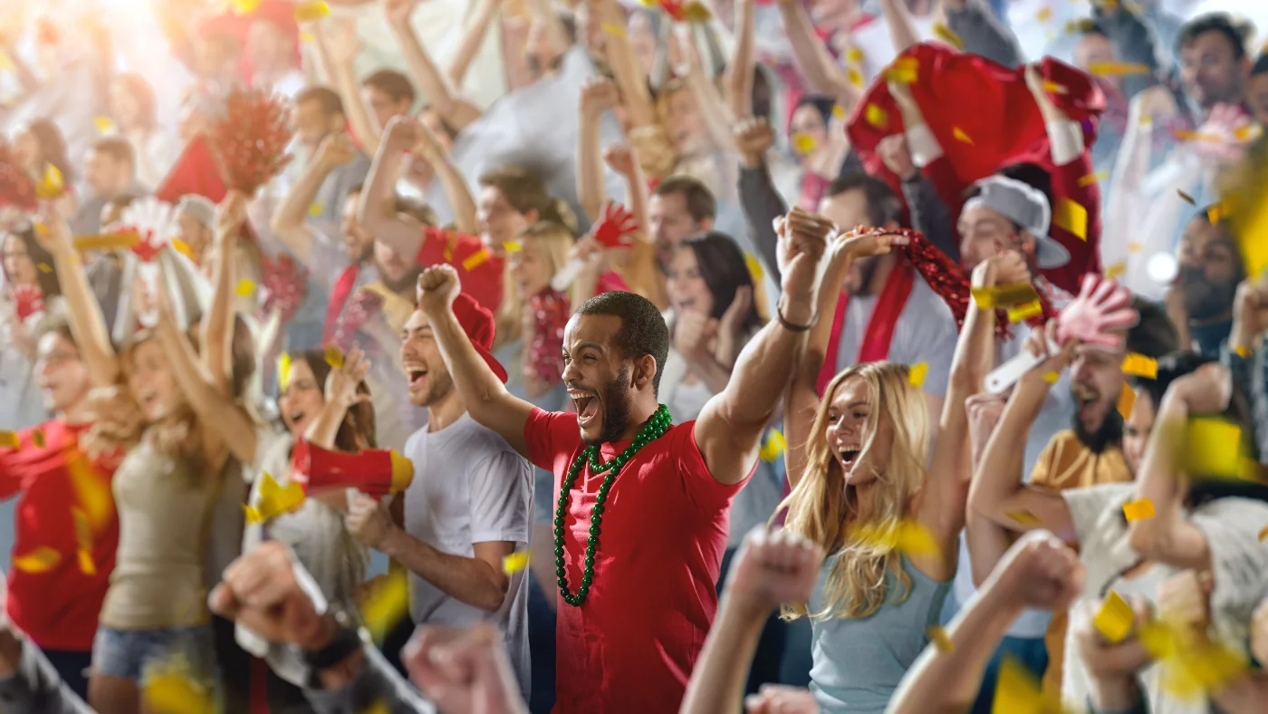 sports fans in red shirts cheering their team from the stands